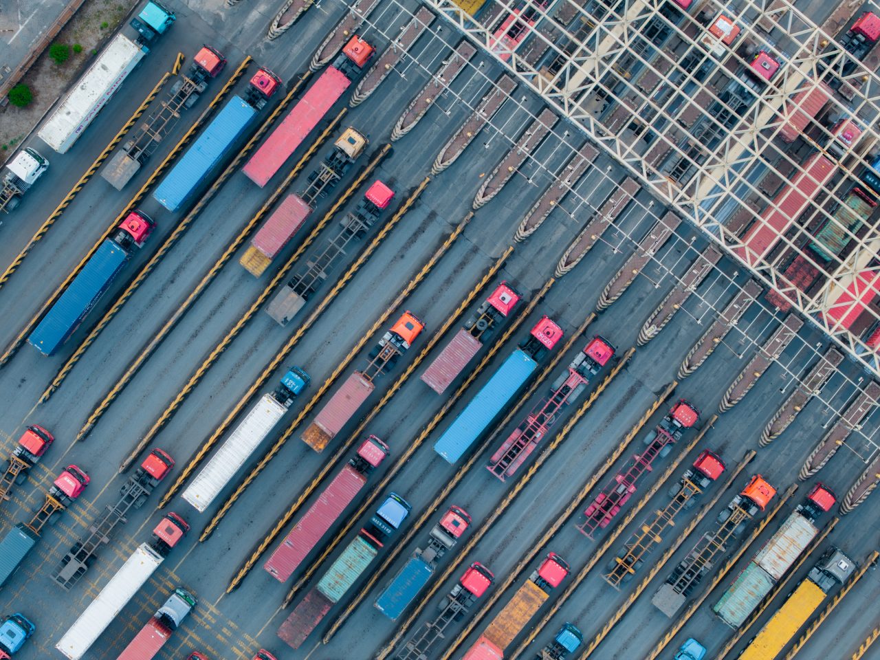 Aerial view of an intermodal freight yard with rows of container trucks and organized transport lanes.