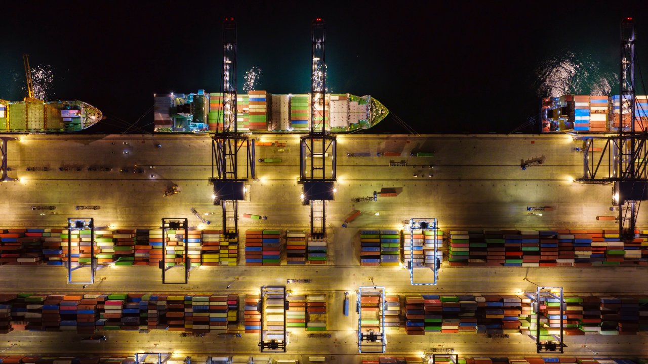 Container terminal working vessels at night under floodlights.
